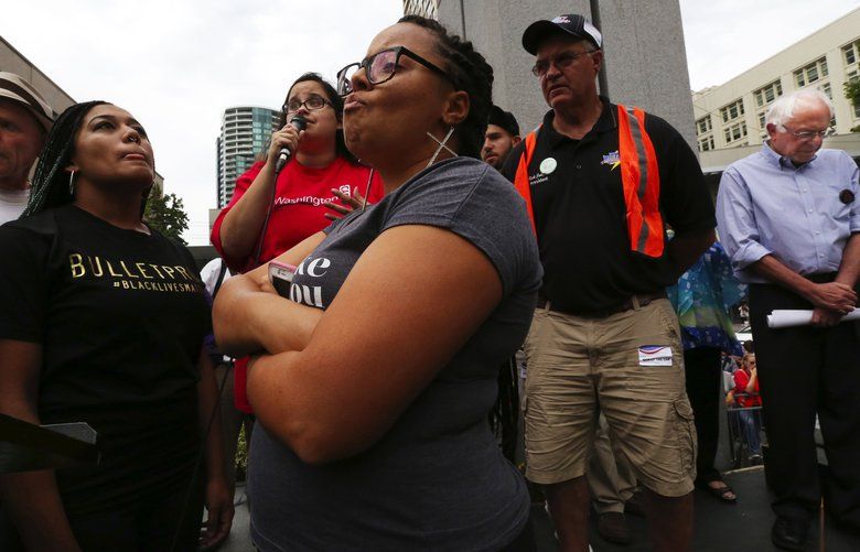 Democratic presidential candidate Sen. Bernie Sanders, I-Vermont, right, waits to resume speaking after the Westlake Park stage is taken over by Black Lives Matter activists Mara Jacqueline Willaford, second from left, and Marissa Johnson, center, Aug. 8, 2015. Rally organizer and emcee Robby Stern, left, allowed them to speak but Sanders was not able to return to the podium, left the stage, walked through the crowd of supporters and then left in a car. (Alan Berner / The Seattle Times)