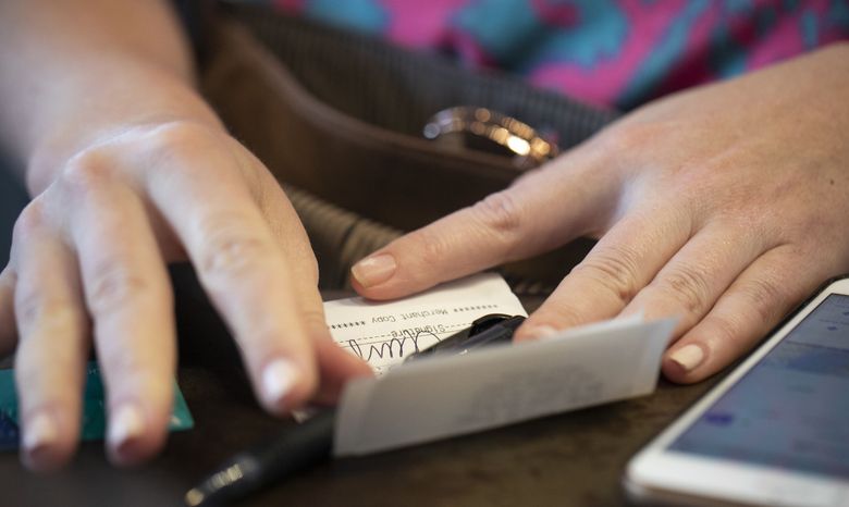FILE – In this Aug. 11, 2019, file photo a woman signs a check at a restaurant in New Orleans. Personal finance rules of thumb can be useful for evaluating how you are doing with your money and for setting financial goals. (Jenny Kane / The Associated Press) credit receipt personal finance