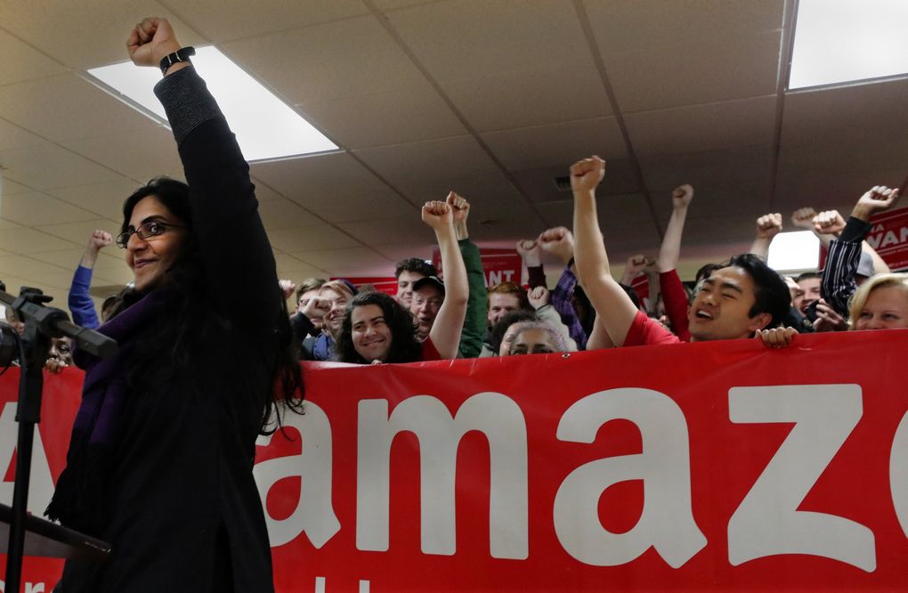 Fist raised in victory, Seattle City Councilmember Kshama Sawant greets supporters holding a “Tax Amazon” banner after late vote counts pulled her ahead of challenger Egan Orion in the November elections. (Alan Berner / The Seattle Times)