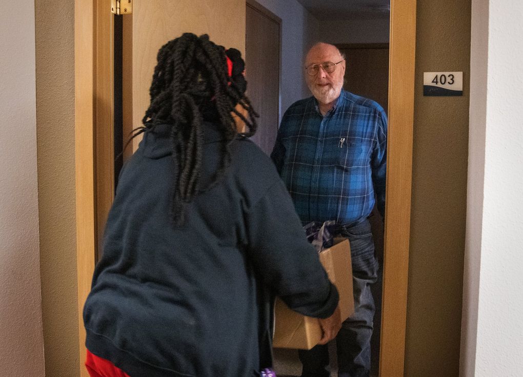 Keith Orchard opens his door to Fai Mathews, a Meals on Wheels driver. Orchard was in the Marine Corps, went to Vietnam and worked for many years. Getting around is harder now. (Ellen M. Banner / The Seattle Times)