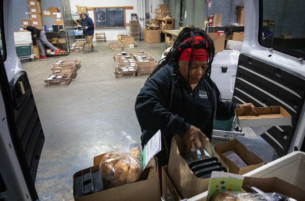 Fai Mathews loads her van with food she will be delivering. She does more than drop off groceries and prepared meals. She gets to know the people on her route. (Ellen M. Banner / The Seattle Times)