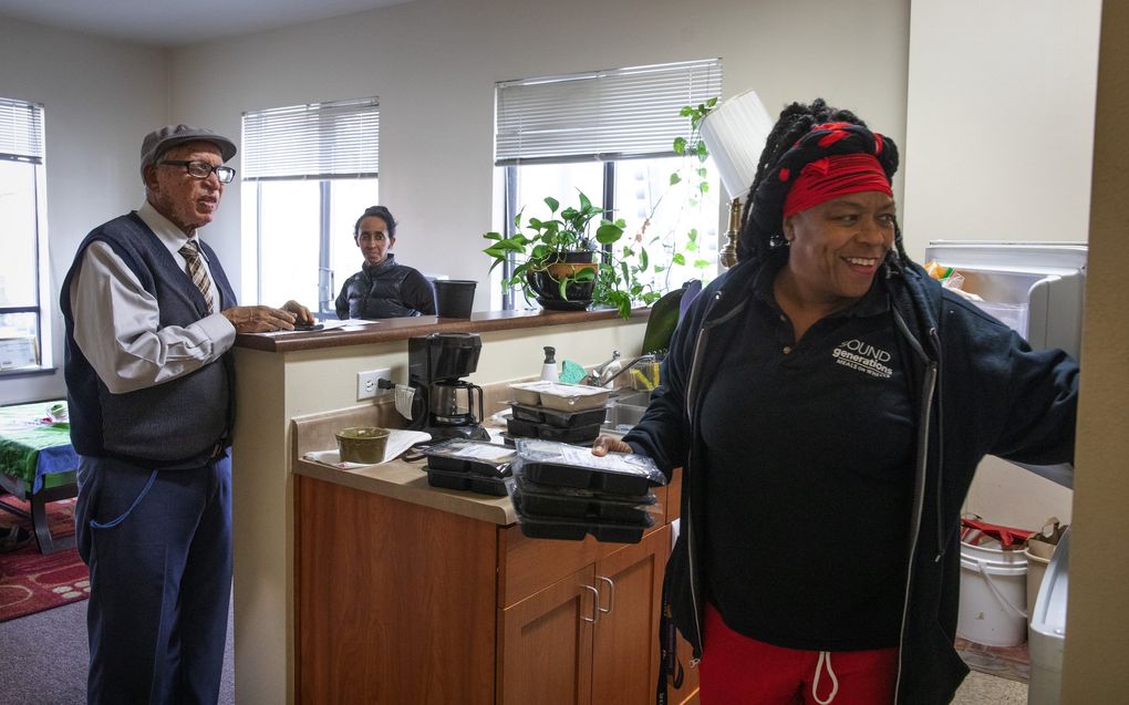 As Asefa Tessema, left, watches, Fai Mathews, a driver for Meals on Wheels, puts prepared meals into the freezer in his Seattle home. At center is Sara Alemeseged, who comes by to help Tessma. (Ellen M. Banner / The Seattle Times)