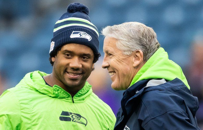 Seattle hip hop and rap singer Macklemore greets Seattle Seahawks  quarterback Russell Wilson before an NFL football game between the Seahawks  and Tennessee Titans, Sunday, Oct. 13, 2013, in Seattle. (AP Photo/Elaine