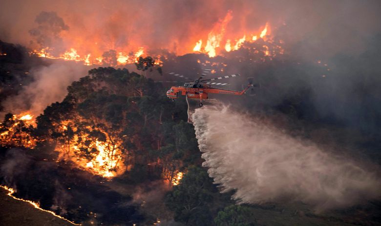 A photo provided by the State Government of Victoria, Australia, shows a helicopter dumping water on a wildfire near Bairnsdale on Tuesday, Dec. 31, 2019.  The country’s east coast is dotted with apocalyptic scenes on the last day of the warmest decade on record in Australia.  (State Government of Victoria via The New York Times) **EDITORIAL USE ONLY**  XNYTF XNYTF (STATE GOVERNMENT OF VICTORIA / NYT)