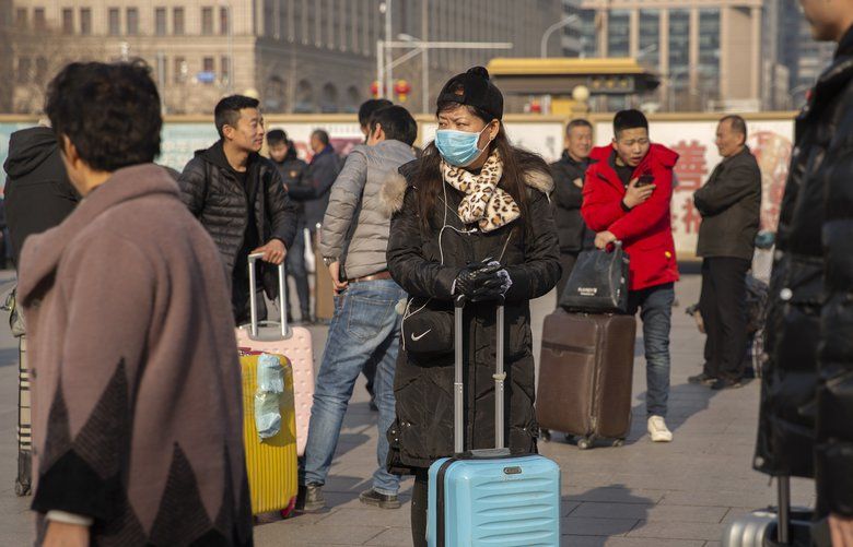 A traveler wears a facemask as she stands near the Beijing Railway Station in Beijing, Friday, Jan. 17, 2020. A second person has died from a new form of coronavirus in central China, health authorities said late Thursday. (AP Photo/Mark Schiefelbein) XMAS112 XMAS112