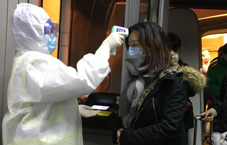 Health Officials in hazmat suits check body temperatures of passengers arriving from the city of Wuhan Wednesday, Jan. 22, 2020, at the airport in Beijing, China. Nearly two decades after the disastrously-handled SARS epidemic, Chinaâ€™s more-open response to a new virus signals its growing confidence and a greater awareness of the pitfalls of censorship, even while the government is as authoritarian as ever. (AP Photo Emily Wang) BKWS326 BKWS326