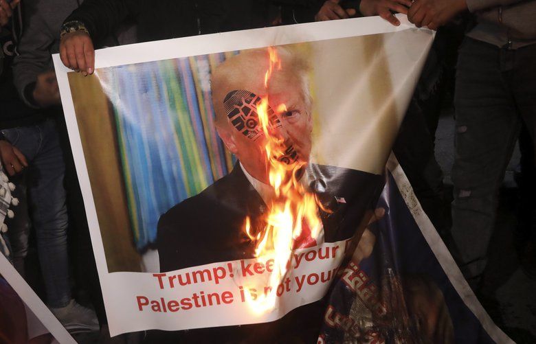 Palestinian burn a poster showing U.S. President Donald Trump as they protest the American peace plan in Bethlehem, Monday, Jan. 27, 2020. Israeli Prime Minister Benjamin Netanyahu arrived in Washington Sunday night vowing to “make history” at a planned meeting with President Donald Trump for the unveiling of the U.S. administration’s much-anticipated plan to resolve the Israeli-Palestinian conflict. (AP Photo/Mahmoud Illean) DV116 DV116