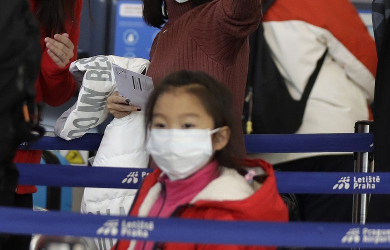Passengers wearing masks wait in a line to check-in to a flight to Shanghai at the Vaclav Havel International Airport in Prague, Czech Republic, Monday, Jan. 27, 2020. Prague’s international airport is launching an information campaign for travellers who develop symptoms possibly linked to a new coronavirus illness. (AP Photo/Petr David Josek) PJO103 PJO103
