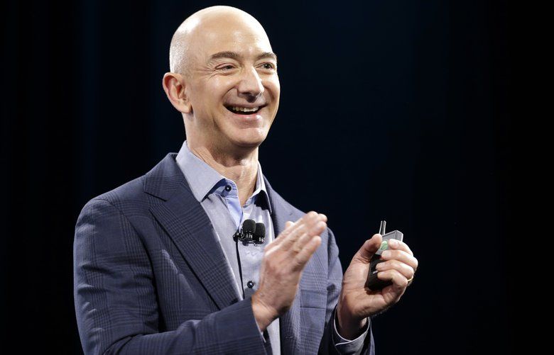 Amazon CEO Jeff Bezos holds a slide show controller and applauds at the start of the launch event for the new Amazon Fire Phone, Wednesday, June 18, 2014, in Seattle. (AP Photo/Ted S. Warren) WATW115