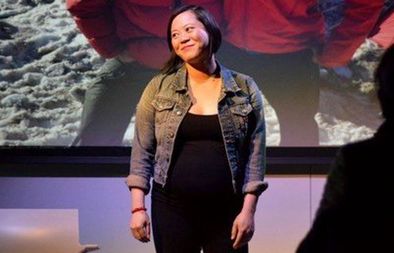 Susan Lieu performing ‘140 LBS: How Beauty Killed My Mother.â€™ Behind her is an image of her and her husband Marvin mountaineering in the Pacific Northwest.
