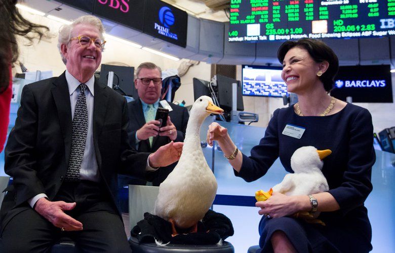 Dan Amos, chairman and chief executive officer of Aflac Inc., left and Catherine Hernandez-Blades, chief brand and communications officer of Aflac Inc., right, pet the Aflac duck on the floor of the New York Stock Exchange (NYSE) in New York, U.S., on Monday, September 10, 2018. Photographer: Michael Nagle/Bloomberg 775225583