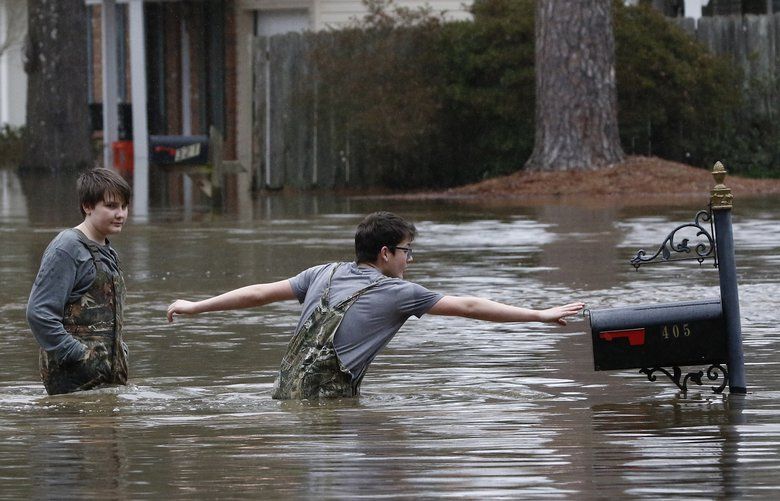 Blaine Henderson right, reaches to tag a mailbox as Pearl River as he and his friend Jonah Valdez, both 12, play in the floodwaters of this northeast Jackson, Miss., neighborhood, Sunday, Feb. 16, 2020. Residents of Jackson braced Sunday for the possibility of catastrophic flooding in and around the Mississippi capital as the Pearl River rose precipitously after days of torrential rain. (AP Photo/Rogelio V. Solis) MSRS117 MSRS117