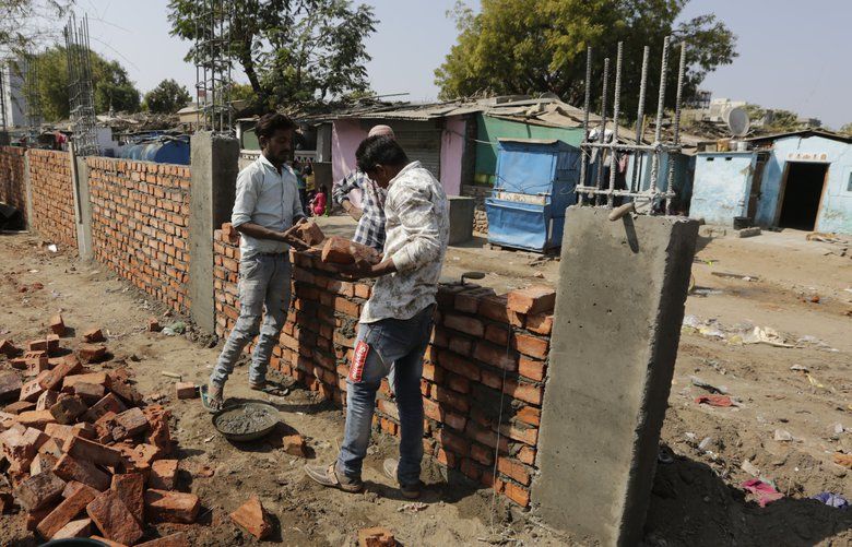 FILE- In this Monday, Feb. 17, 2020, file photo, Indian workers construct a wall in front of a slum ahead of U.S. President Donald Trump’s visit, in Ahmadabad, India. A half-kilometer (1,640-foot) brick wall has been hastily erected in India’s Gujarat state ahead of a visit by U.S. President Donald Trump, with critics saying it was built to block the view of a slum area inhabited by more than 2,000 people. (AP Photo/Ajit Solanki, File) XDEL101 XDEL101