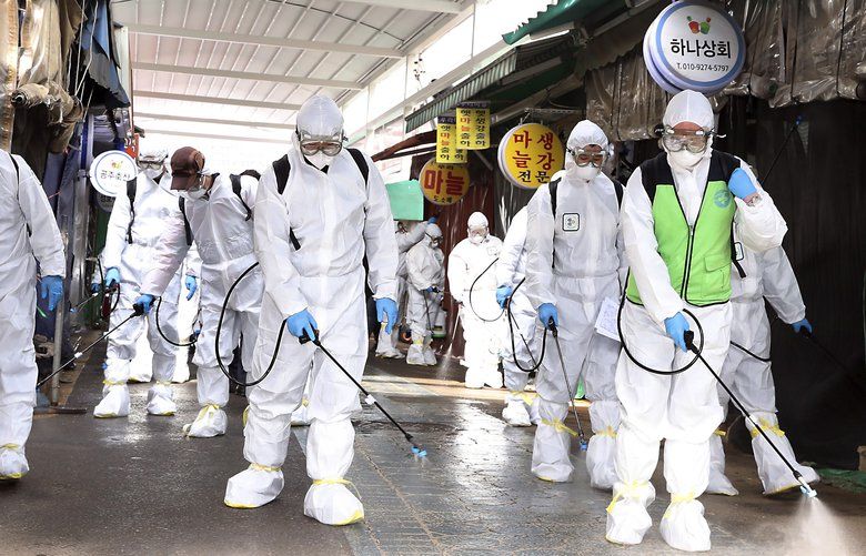 Workers wearing protective suits spray disinfectant as a precaution against the coronavirus at a market in Bupyeong, South Korea, Monday, Feb. 24, 2020. South Korea reported another large jump in new virus cases Monday a day after the the president called for “unprecedented, powerful” steps to combat the outbreak that is increasingly confounding attempts to stop the spread. (Lee Jong-chul/Newsis via AP) SEL807 SEL807