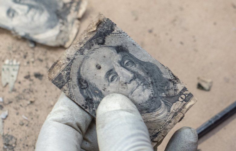 An examiner cuts the image of Benjamin Franklin from damaged $100 bills. Photographed Jan. 16, 2020, in Washington, D.C. MUST CREDIT: Photo for The Washington Post by André Chung