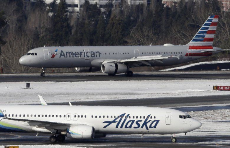 Alaska Airlines planes and one from American Airlines taxi, Tuesday, Feb. 5, 2019, near a snow-bordered runway at Seattle-Tacoma International Airport in Seattle. (AP Photo/Ted S. Warren) OTK