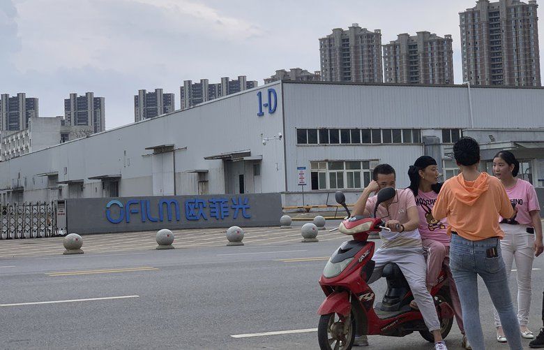 In this June 5, 2019, photo, neighborhood residents chat near the entrance to an OFILM factory in Nanchang in eastern China’s Jiangxi province. The Associated Press has found that OFILM, a supplier of major multinational companies, employs Uighurs, an ethnic Turkic minority, under highly restrictive conditions, including not letting them leave the factory compound without a chaperone, worship, or wear headscarves. (AP Photo/Ng Han Guan) XHG102 XHG102