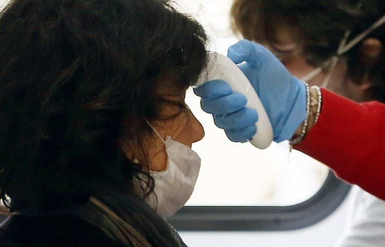 A blood donor has her temperature checked inside a Red Cross mobile center, in Rome Tuesday, March 17, 2020. After the initial scare due to the coronavirus outbreak, many donors responded to the Red Cross appeal to continue giving their blood. For most people, the new coronavirus causes only mild or moderate symptoms. For some it can cause more severe illness, especially in older adults and people with existing health problems. (Cecilia Fabiano/LaPresse via AP) XAP801 XAP801
