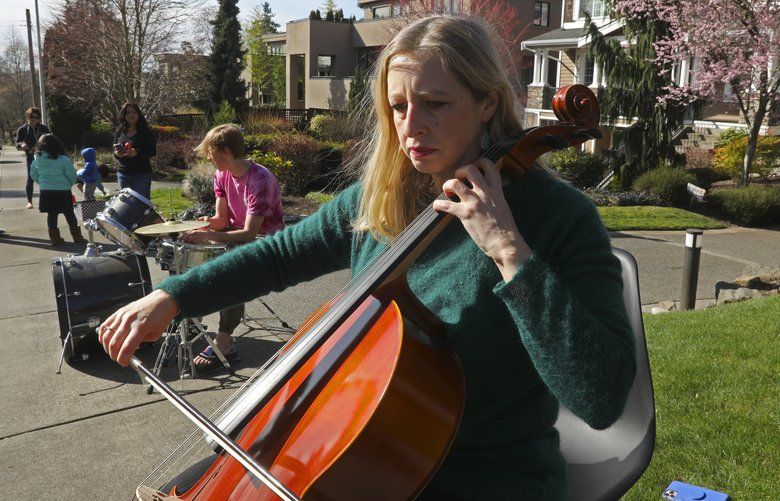 Silvia Bajardi, who is Italian, right, plays J.S. Bach on her cello, joined by her son Nick Davis on drums in front of their home, as neighbors show solidarity during the coronavirus outbreak in Kirkland, March 15, 2020. Organizing on social media, neighbors said they were inspired by the viral video of Italian neighbors musically coming together on balconies at an apartment building. 213349