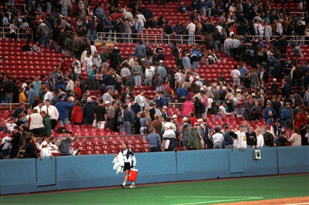 The ballgirl leaves the field and Mariner fans make a hasty but orderly exit from the Kingdome after the ballgame was suspended because of an earthquake. (Mark Harrison / The Seattle Times)