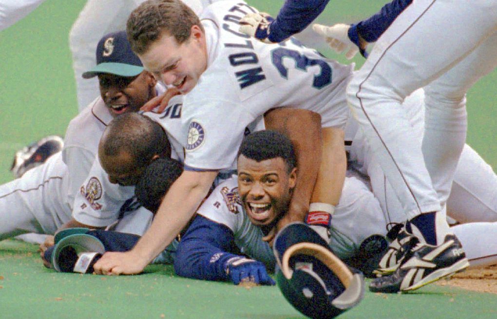 Seattle Mariners’ Ken Griffey Jr. smiles from beneath a pile of teammates who mobbed him after he scored the winning run in the bottom of the 11th inning of Game 5 of the ALDS against the New York Yankees in Seattle, October 8, 1995. (Elaine Thompson / The Associated Press)