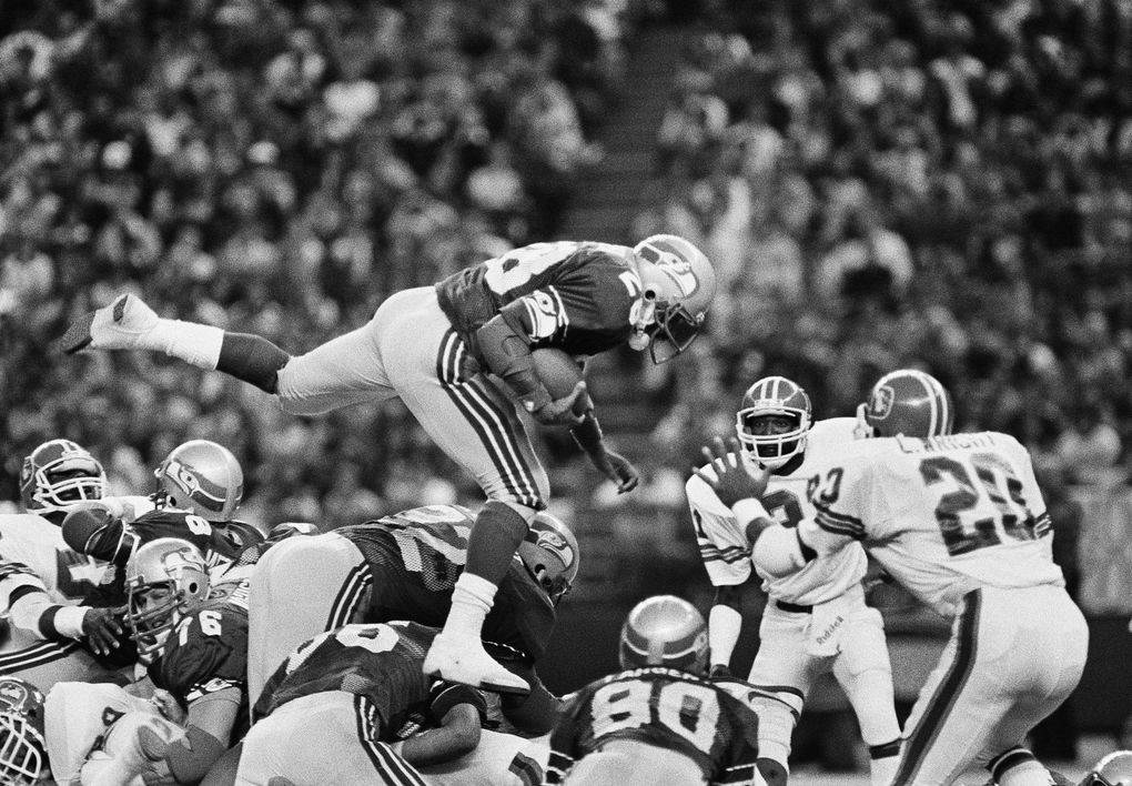 Seattle Seahawk running back Curt Warner leaps over a pile of players as he gains yardage against the Denver Broncos in the Kingdome at Seattle, on Dec. 25, 1983. Warner gained 99 yards on 23 carries as the Seahawks beat the Broncos in their NFL wildcard game 31-7. (Jeff Larson / AP)