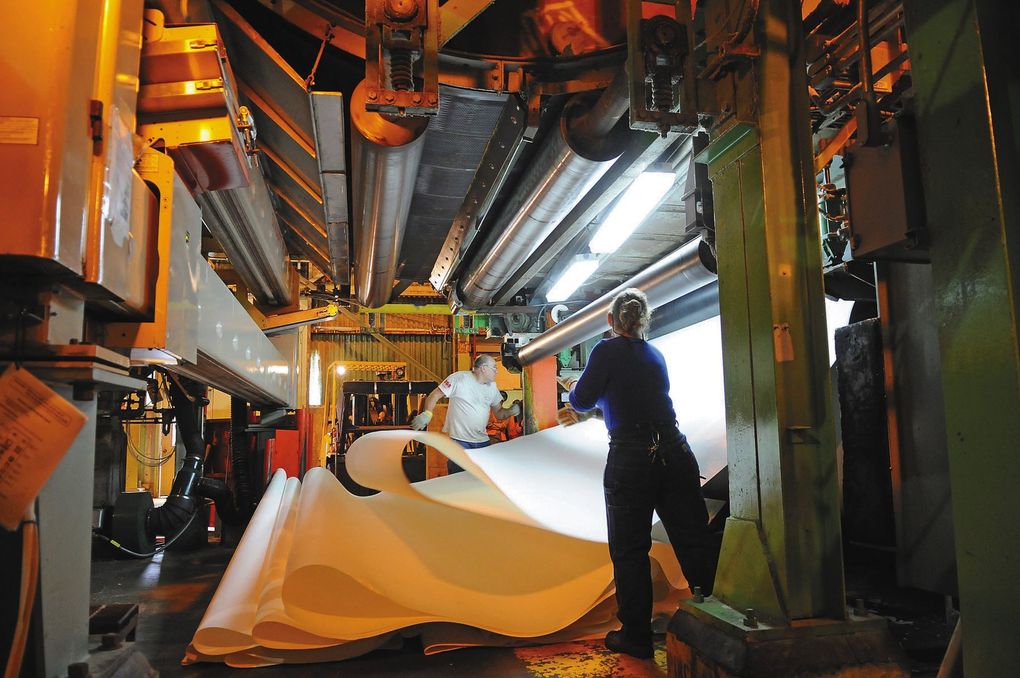 Workers at Cosmo Specialty Fibers respool a sheet of product through the production line. (MacLeod Pappidas / The Daily World)