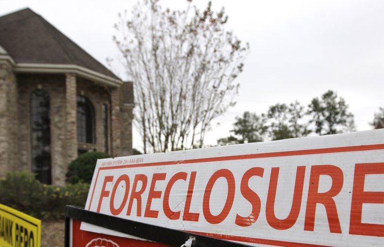FILE – A Jan. 10, 2009 file photo shows a bank repo and foreclosure for sale signs outside a foreclosed home in Houston.   (AP Photo/David J. Phillip/file)