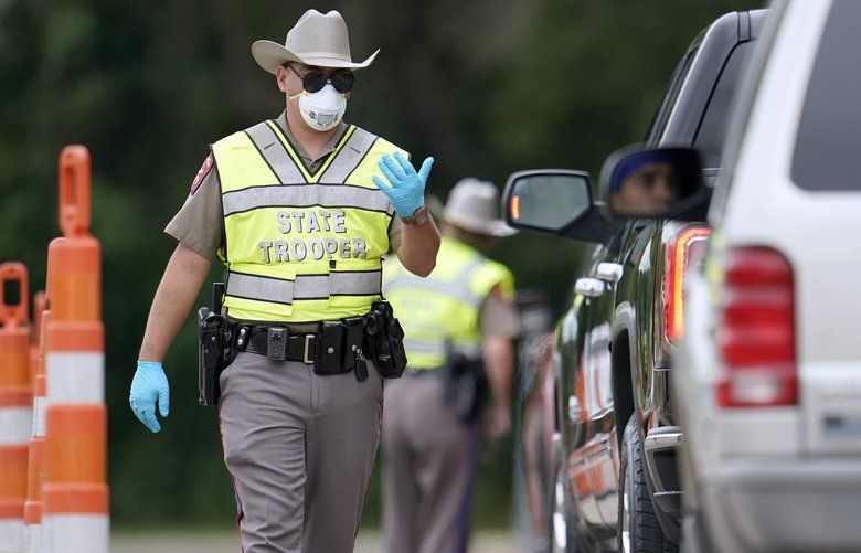 A Texas Department of Public Safety State Trooper directs traffic at a checkpoint in Orange, Texas, near the Louisiana state border, Monday, April 6, 2020. The troopers are checking motorists crossing the border between Louisiana and Texas on I-10 to determine if they need to self-quarantine for 14 days to comply with an executive order from Gov. Greg Abbott due to the COVID-19 outbreak. (AP Photo/David J. Phillip) TXDP109 TXDP109