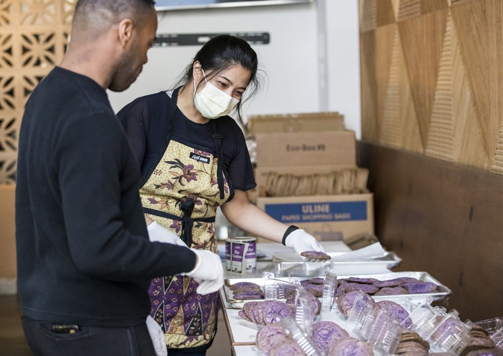 Hood Famous Cafe + Bar co-owner Chera Amlag and cafe manager Anton Coleman package ube cookies for delivery. Hood Famous was one of the small businesses awarded a $10,000 coronavirus relief grant from the city of Seattle. (Amanda Snyder / The Seattle Times)