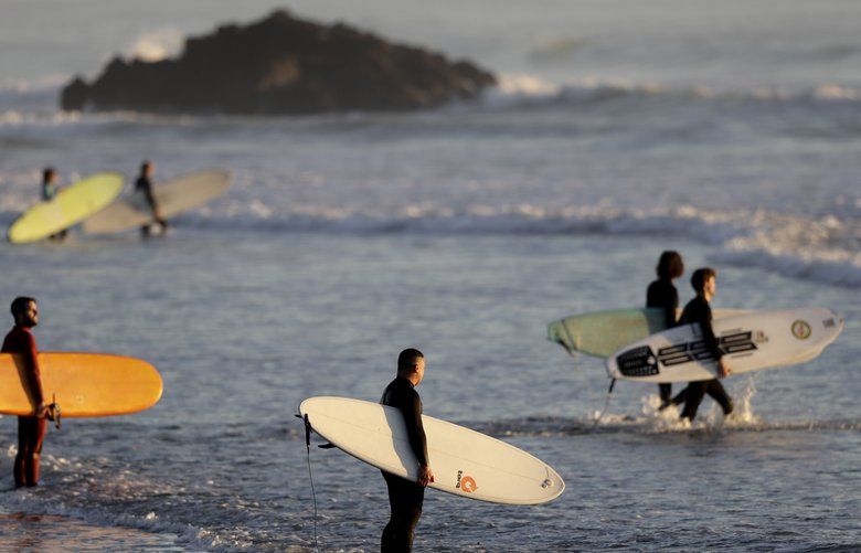 Surfers prepare to enter the water for a sunrise surf at Sumner Beach as level four COVID-19 restrictions are eased in Christchurch, New Zealand, Tuesday, April 28, 2020. New Zealand eased its strict lockdown restrictions to level three at midnight to open up certain sections of the economy but social distancing rules will still apply. (AP Photo/Mark Baker) XMB106 XMB106