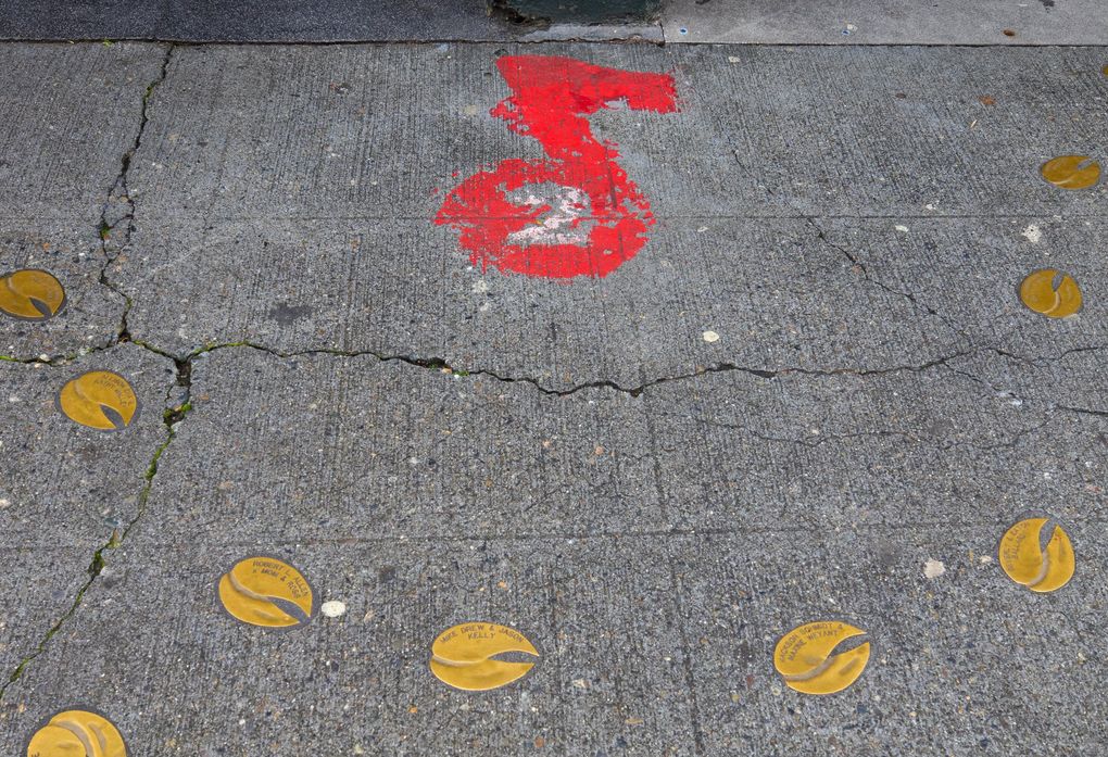 Designated busking spots at the Market are marked with a red musical note. The “2” tells how many buskers are allowed to perform there at the same time. (Ellen M. Banner / The Seattle Times)