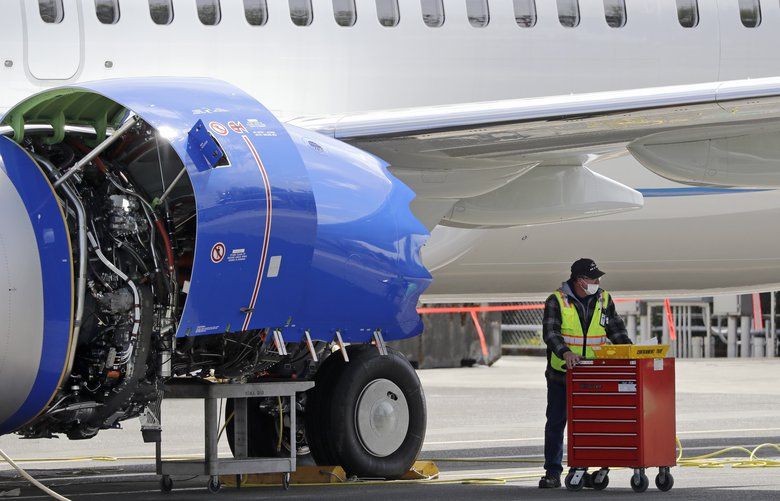 A Boeing employee moves a work cart away from the engine of a Boeing 737 MAX jet at a Boeing airplane manufacturing plant Wednesday, April 29, 2020, in Renton, Wash. Boeing says it will cut about 10% of its work force and slow production of planes as it deals with the ongoing grounding of its best-selling plane and the coronavirus pandemic. With air travel falling sharply because of the virus, airlines have delayed orders and deliveries of new planes, reducing Boeing’s revenue. (AP Photo/Elaine Thompson) WAET108 WAET108