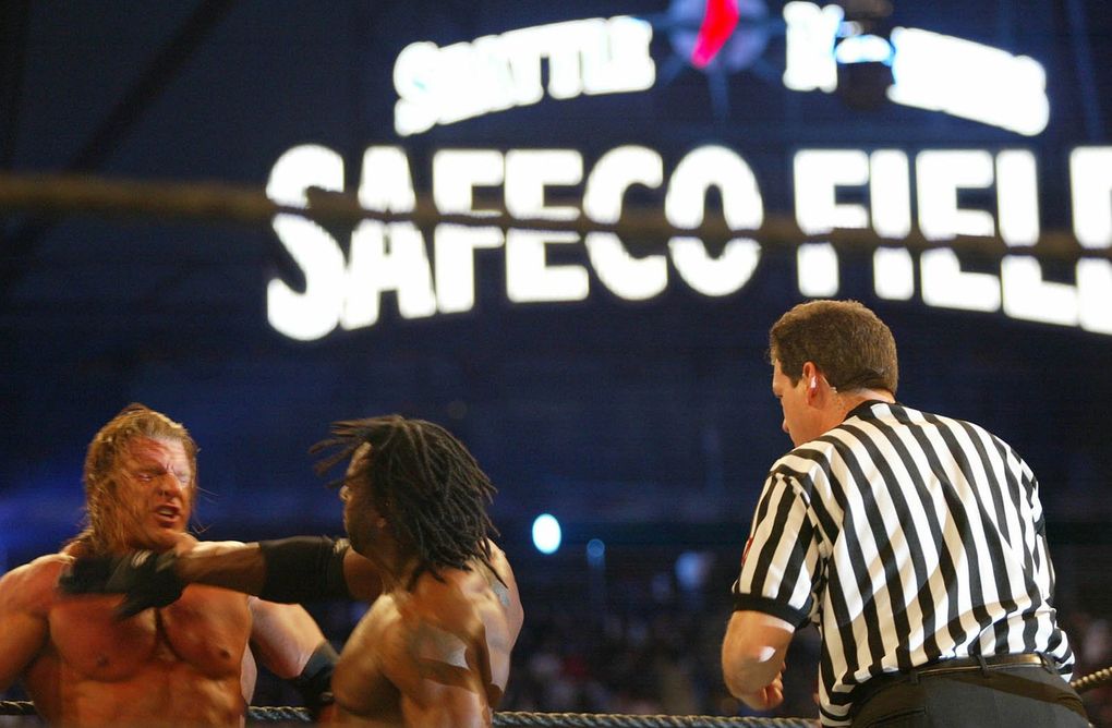 Booker T, center, lays a vicious chop down on Triple H Sunday during WrestleMania XIX at Safeco Field in Seattle in 2003. (John Lok / The Seattle Times)