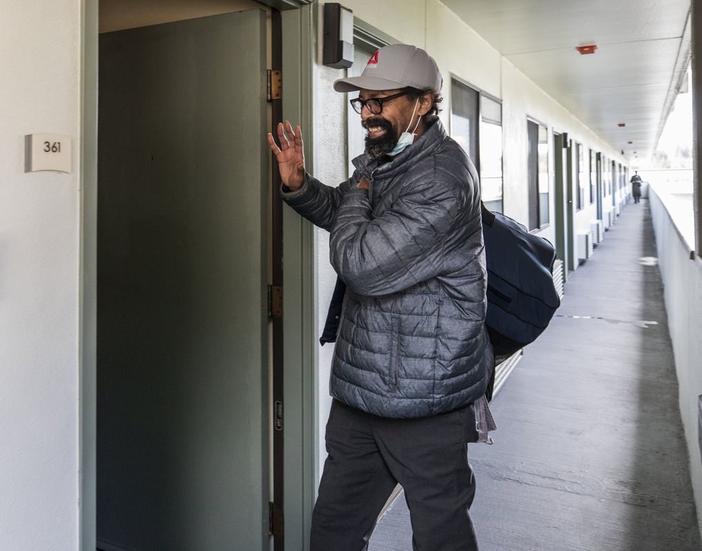 Larry Felder, one of 10 homeless men moving into a motel in Bellevue as part an effort to slow the spread of the novel coronavirus, gives a wave and a smile before entering his room. (Steve Ringman / The Seattle Times)