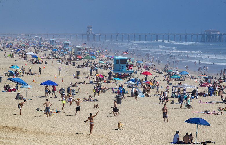Thousands of beach-goers enjoy a warm, sunny day at the beach amid state-mandated stay-at-home and social distancing guidelines in a bid to stave off the coronavirus pandemic in Huntington Beach, Calif., on Saturday, April 25, 2020. (Allen J. Schaben/Los Angeles Times/TNS) 1645964 1645964