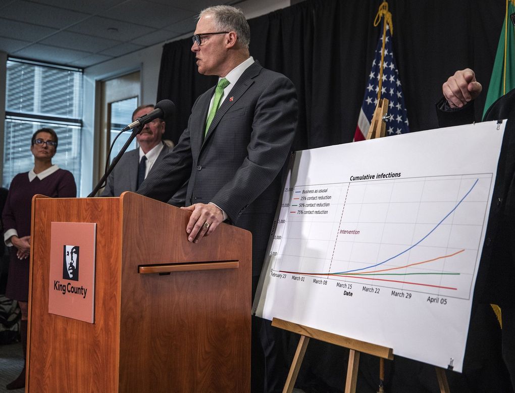 At a news conference on March 11, Gov. Jay Inslee displays a chart showing the state’s predicted rise of coronavirus infections under various social-distancing scenarios. (Steve Ringman / The Seattle Times)