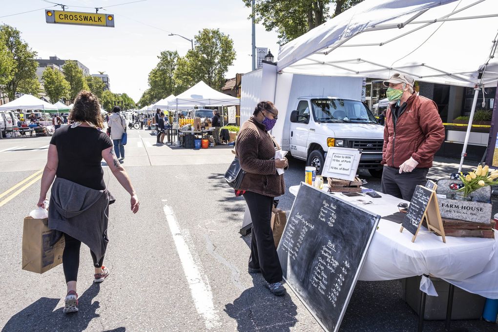 The West Seattle Farmers Market opened for the first time this year under strict guidelines for merchants and social distancing Sunday. There were 969 people officially counted into the market, one of two markets in Seattle to have opened, though on a week-by-week basis, according to Sarah Schu of Neighborhood Farmers Market Alliance, which manages seven farmers markets in the city. The five others have no confirmed dates on which they might reopen. (Dean Rutz / The Seattle Times)