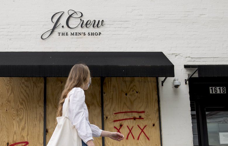 FILE – In this April 29, 2020, file photo, a woman walks past a boarded up J. Crew storefront along 14th Street in Northwest Washington. The parent company of clothing chain J. Crew has filed for Chapter 11 bankruptcy, yet another casualty of the coronavirus pandemic that is wreaking havoc on the retail world. Retail veteran Mickey Drexler led J. Crew for more than a decade, helping it become a coveted fashion brand before it hit a multi-year sales slump.  (AP Photo/Andrew Harnik, File) NY101 NY101