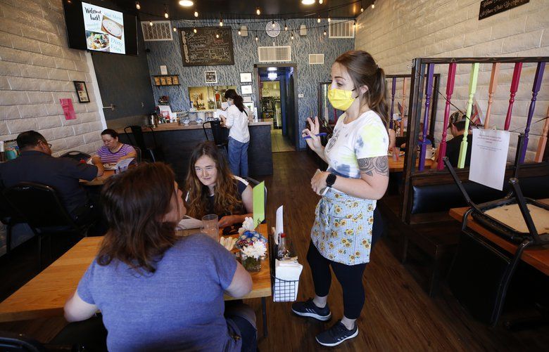 Server Jonnie Overmire goes over the menu for customers Bonnie Sitter, left, and her daughter Abby, 18, at the Lambert House Cafe in Yuba City, Calif., Monday, May 4, 2020. Monday was the first day businesses could open in Sutter County under a modified public health order. (AP Photo/Rich Pedroncelli) 