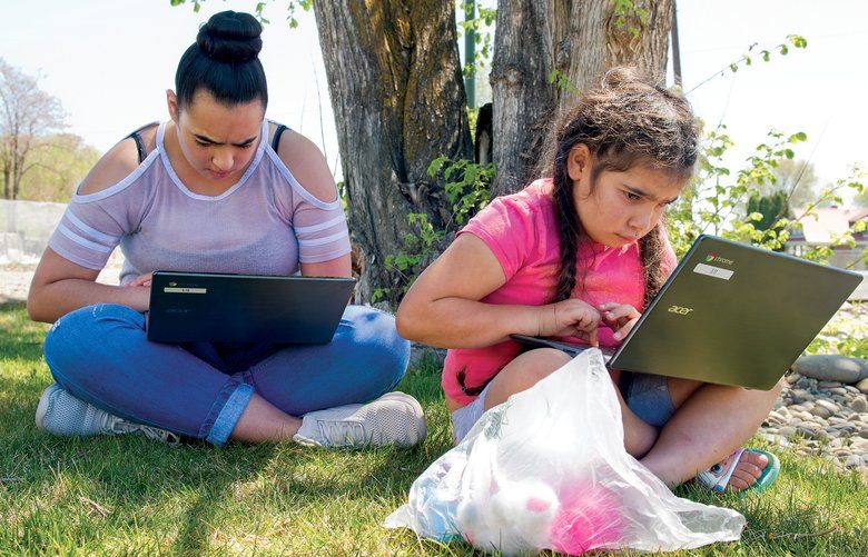 Kindergarten student Veronica Linares and her sister Michele, a Toppenish High School junior, use a Wi-Fi hotspot to access their online learning studies outside the Buena Library on Monday, April 20.