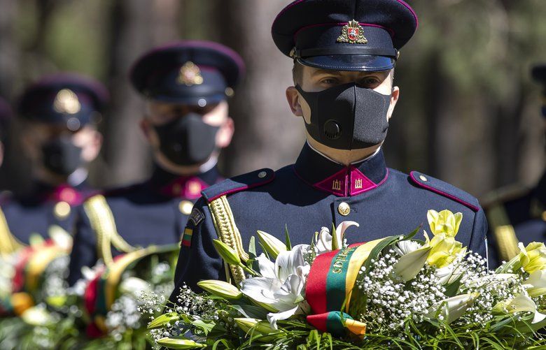 Lithuanian soldiers of the honour guard, wearing face masks to prevent the spread of coronavirus, attend a memorial ceremony marking the 75nd anniversary of the end of World War II at the Paneriai memorial, Vilnius, Lithuania, Friday, May 8, 2020. Victory in Europe Day is celebrated on May 8 to mark the date in 1945 that WWII ended in Europe following Nazi Germany’s surrender of its armed forces. (AP Photo/Mindaugas Kulbis) XMK101 XMK101