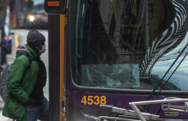 A King County Metro bus driver, wearing a mask, waits for passengers to board his bus on 3rd Ave. near Benaroya Hall between Union Street and University Street Thursday, April 2, 2020.  Drivers are being designated as first responders and have to work.   213546