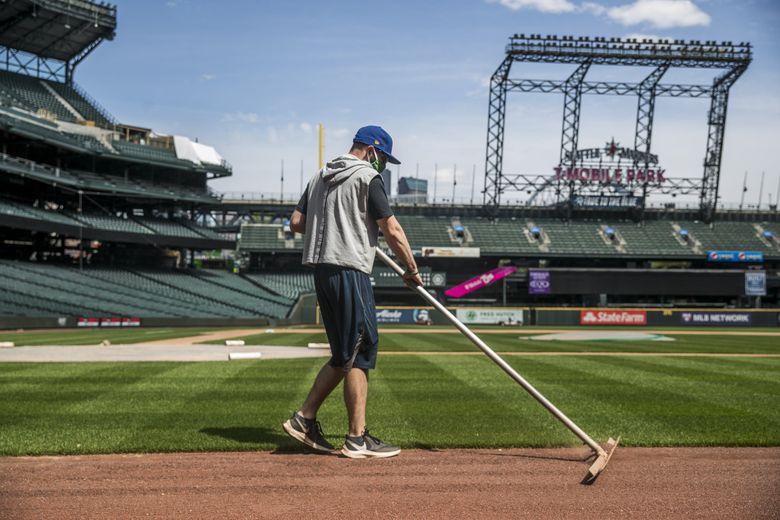 A member of the groundscrew at rakes the infield dirt at T-Mobile Park on Monday, May 11, keeping the field ready for a potential return to baseball.  (Amanda Snyder / The Seattle Times)