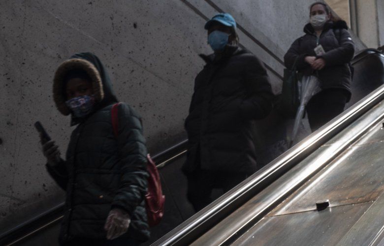 Commuters wearing masks exit a Metro station in New Carrollton, Md., on April 15. MUST CREDIT: Washington Post photo by Michael Robinson Chavez
