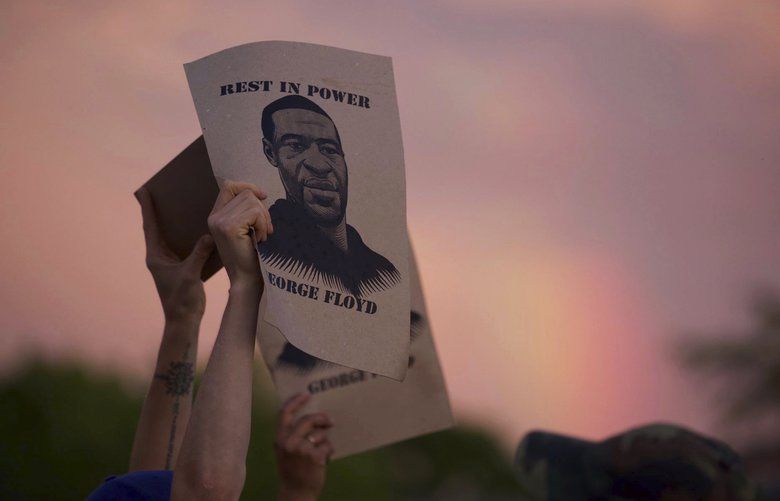 A protester holds a sign with an image of George Floyd during protests Wednesday, May 27, 2020, in Minneapolis against the death of Floyd in Minneapolis police custody earlier in the week. (Christine T. Nguyen/Minnesota Public Radio via AP) MNMPR343 MNMPR343