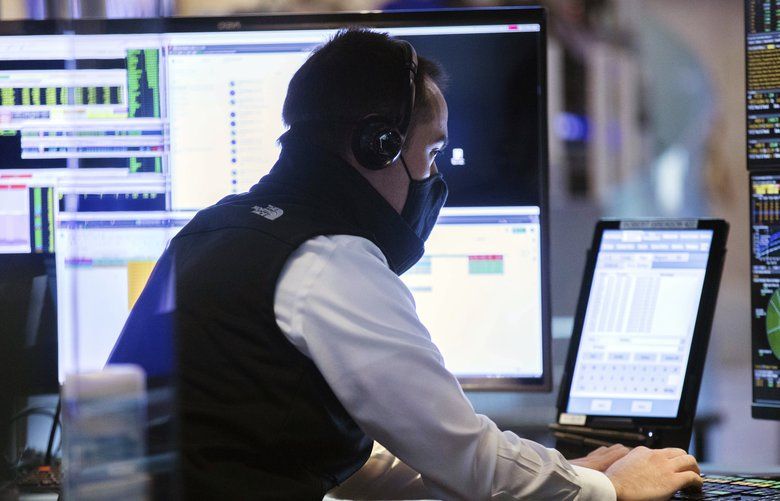 In this photo provided by the New York Stock Exchange, a trader wears a protective face mask as he works on the partially reopened trading floor, Tuesday, May 26, 2020, in New York. Stocks surged on Wall Street in afternoon trading Tuesday, driving the S&P 500 to its highest level in nearly three months, as hopes for economic recovery overshadow worries about the coronavirus pandemic. (Colin Zimmer/New York Stock Exchange via AP) NYRD204 NYRD204