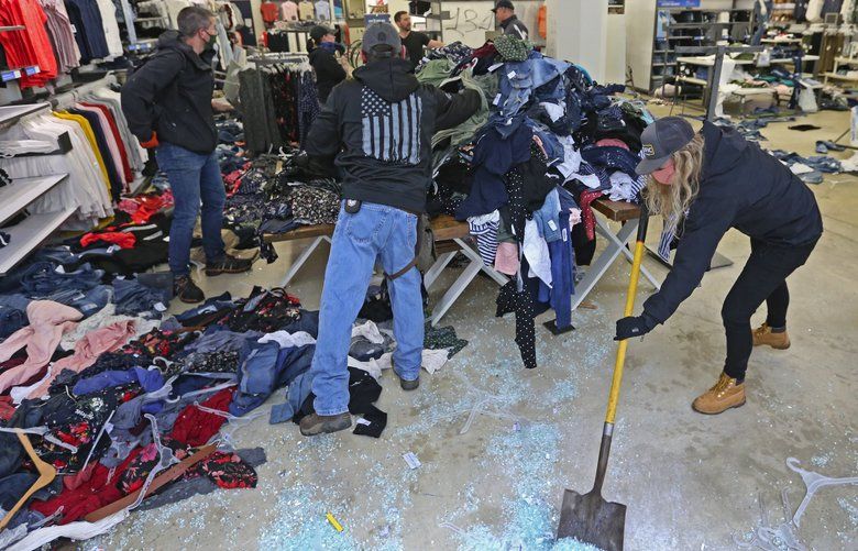 Private citizens cleanup glass and stack clothes at an Old Navy damaged in downtown Seattle Sunday, May 31, 2020, caused by Saturday’s violent protests sparked by the death of George Floyd in Minneapolis. 214108
