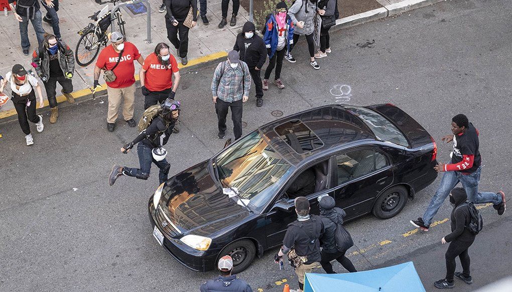 A man drives into the crowd at 11th Avenue and Pine Street on Sunday, injuring at least one person, before exiting the car and brandishing a firearm. (Dean Rutz / The Seattle Times)