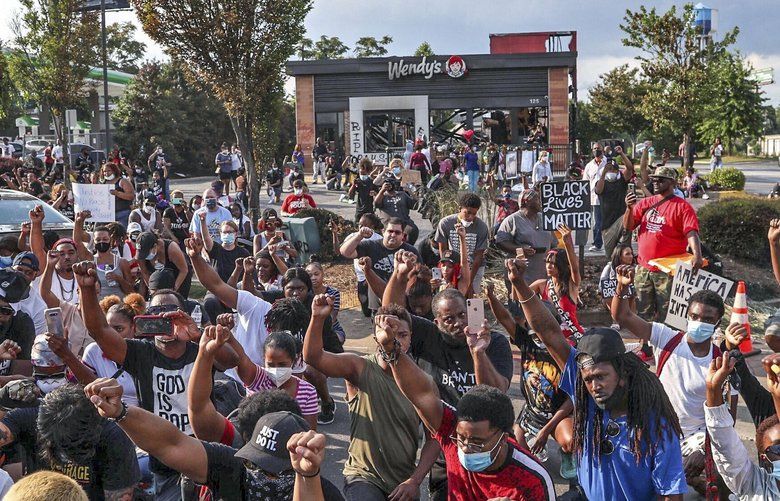 Demonstrators stop for a moment of silence Sunday, June 14, 2020, outside the Wendy’s restaurant in Atlanta where Rayshard Brooks was fatally shot by a police officer Friday night. (Alyssa Pointer/Atlanta Journal-Constitution via AP) GAATJ327 GAATJ327